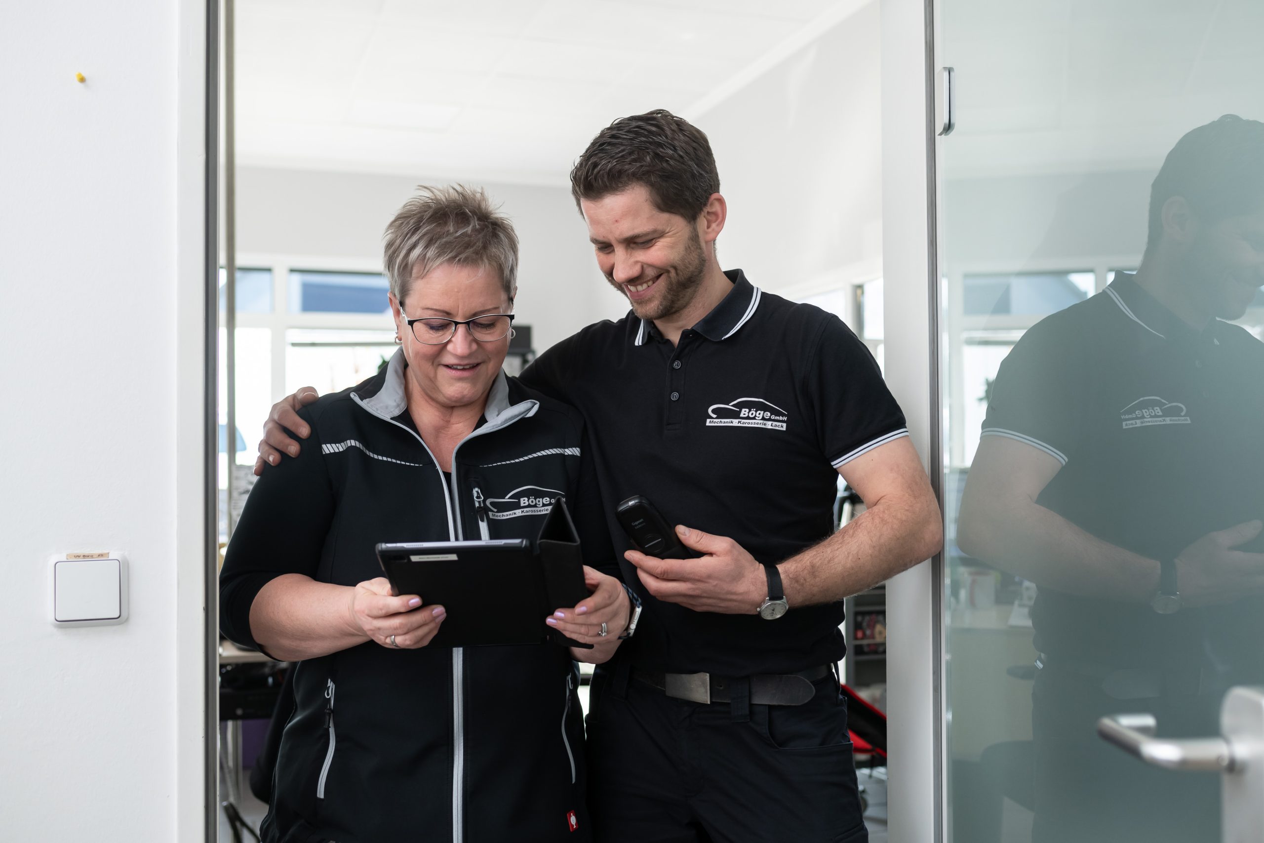 Eine Frau und ein Mann vom Bosch Car Service stehen an einem Tresen und reden miteinander.